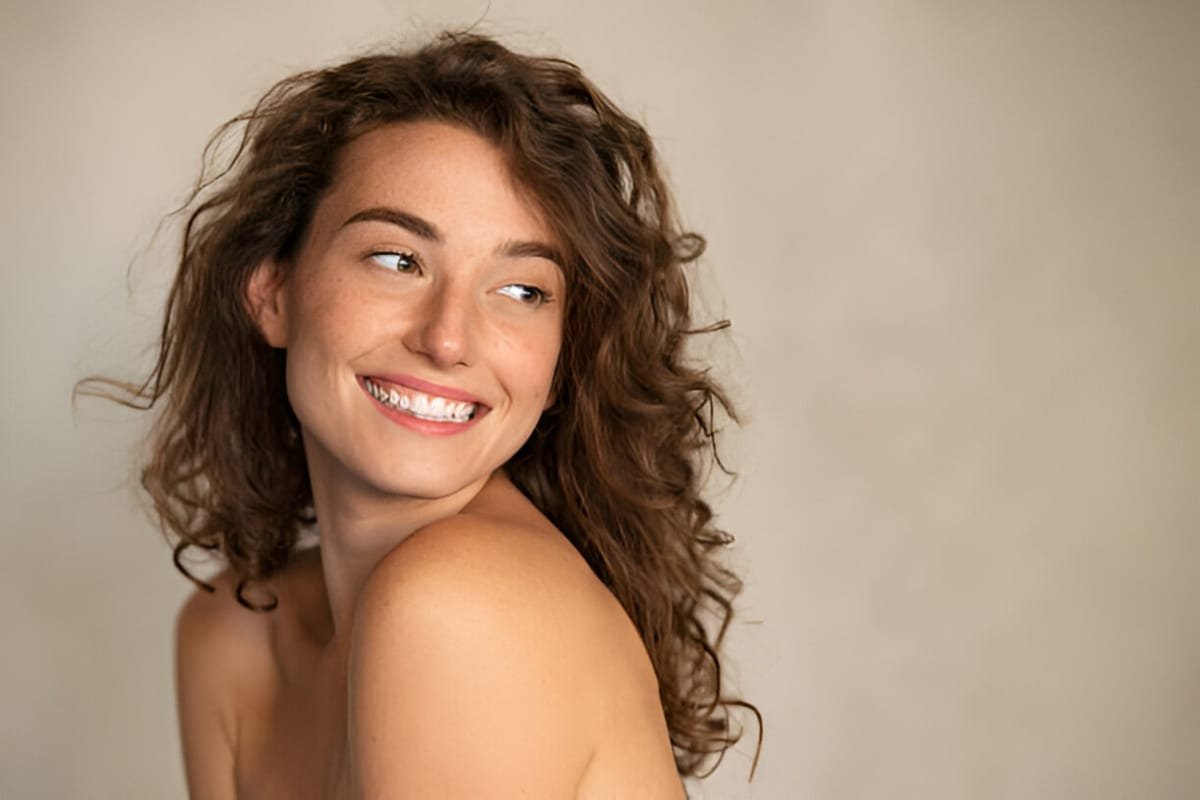 smiling girl enjoying beauty treatment on beige background